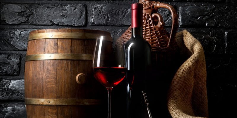 red wine in cellar with barrel and basket
